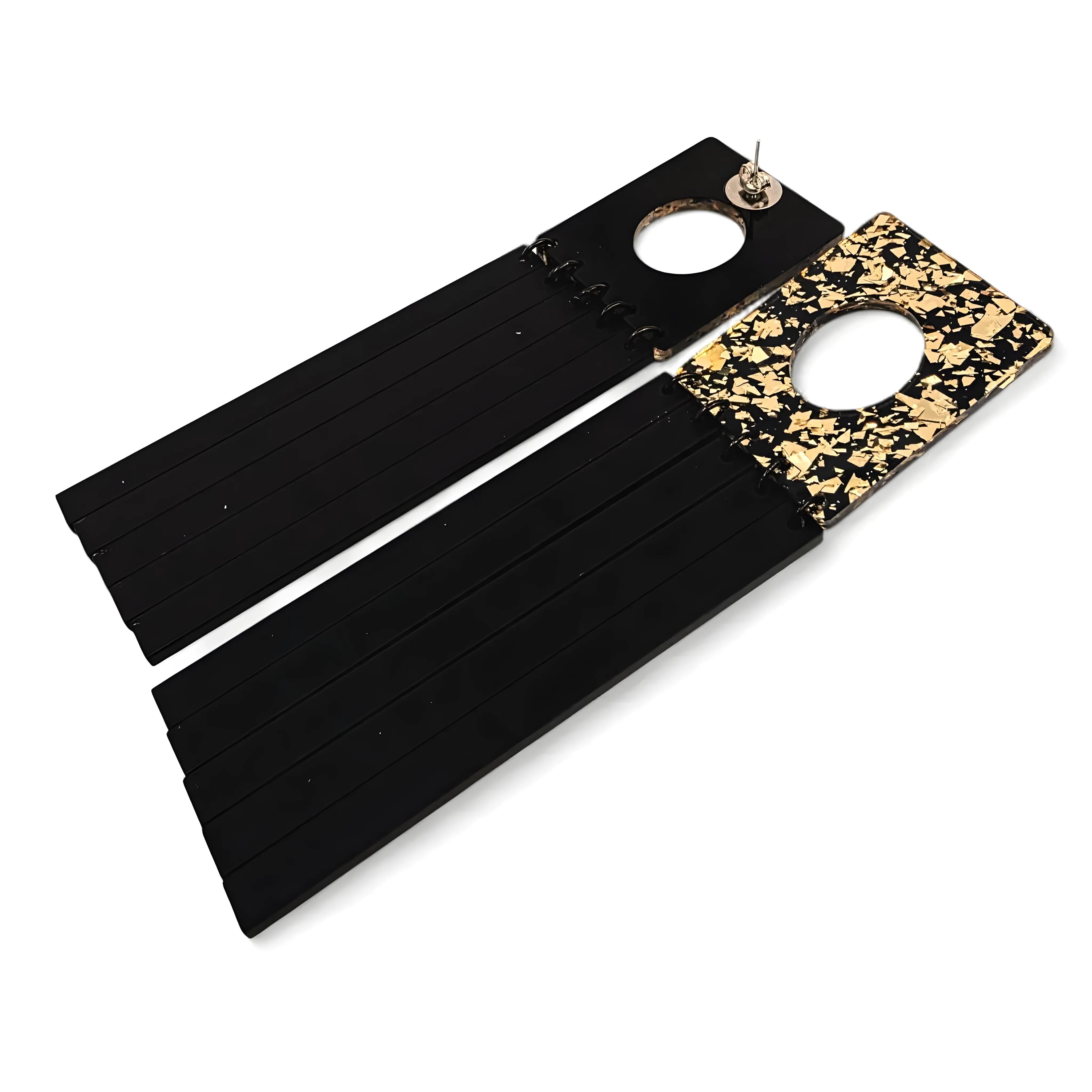 Brincos geométricos pretos com base quadrada dourada marmorizada vistos de costas, mostrando o fecho