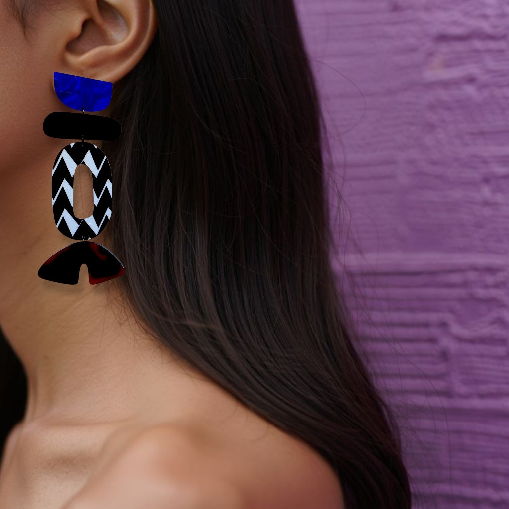 Brinco médio geométrico assimétrico com formas coloridas em preto, branco, azul e tortoise usado na orelha de uma mulher