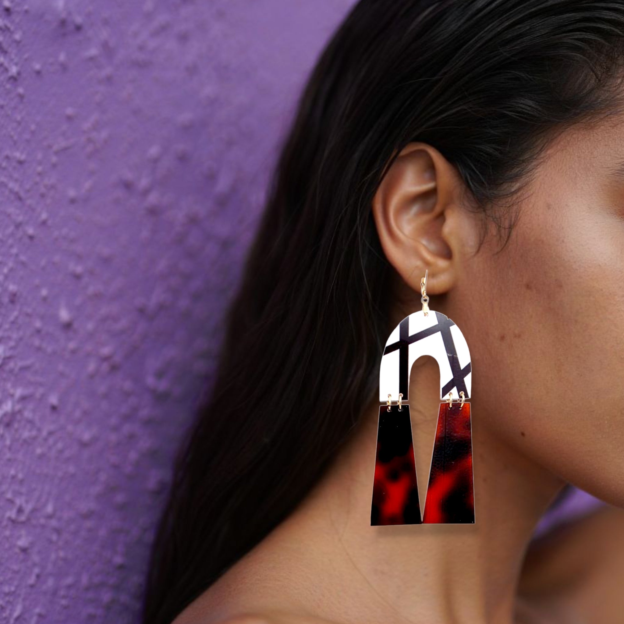 Brinco médio geométrico com padrão tartaruga castanho e detalhe branco usado na orelha de uma mulher