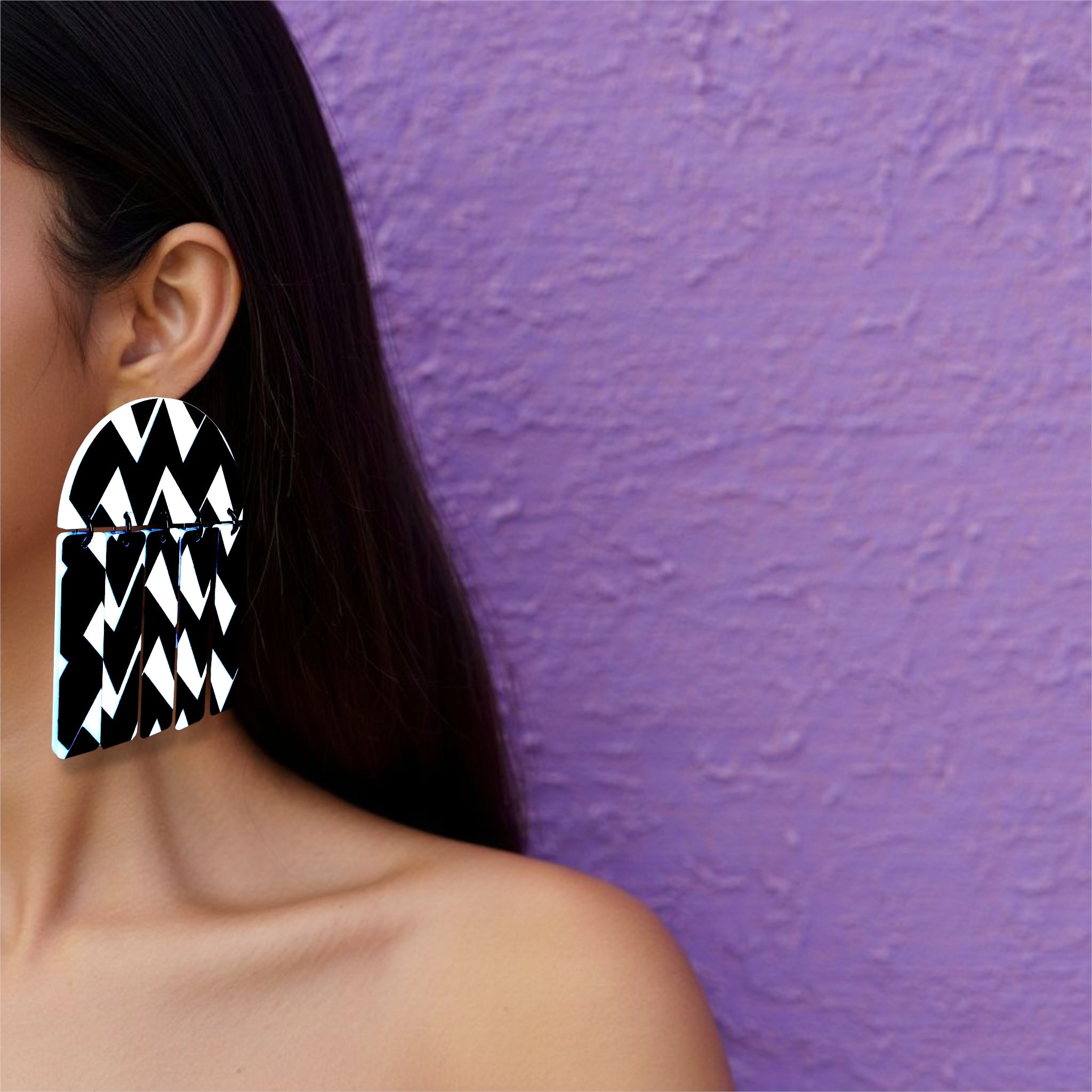 Brinco maxi geométrico preto e branco com padrão zigue-zague usado na orelha de uma mulher