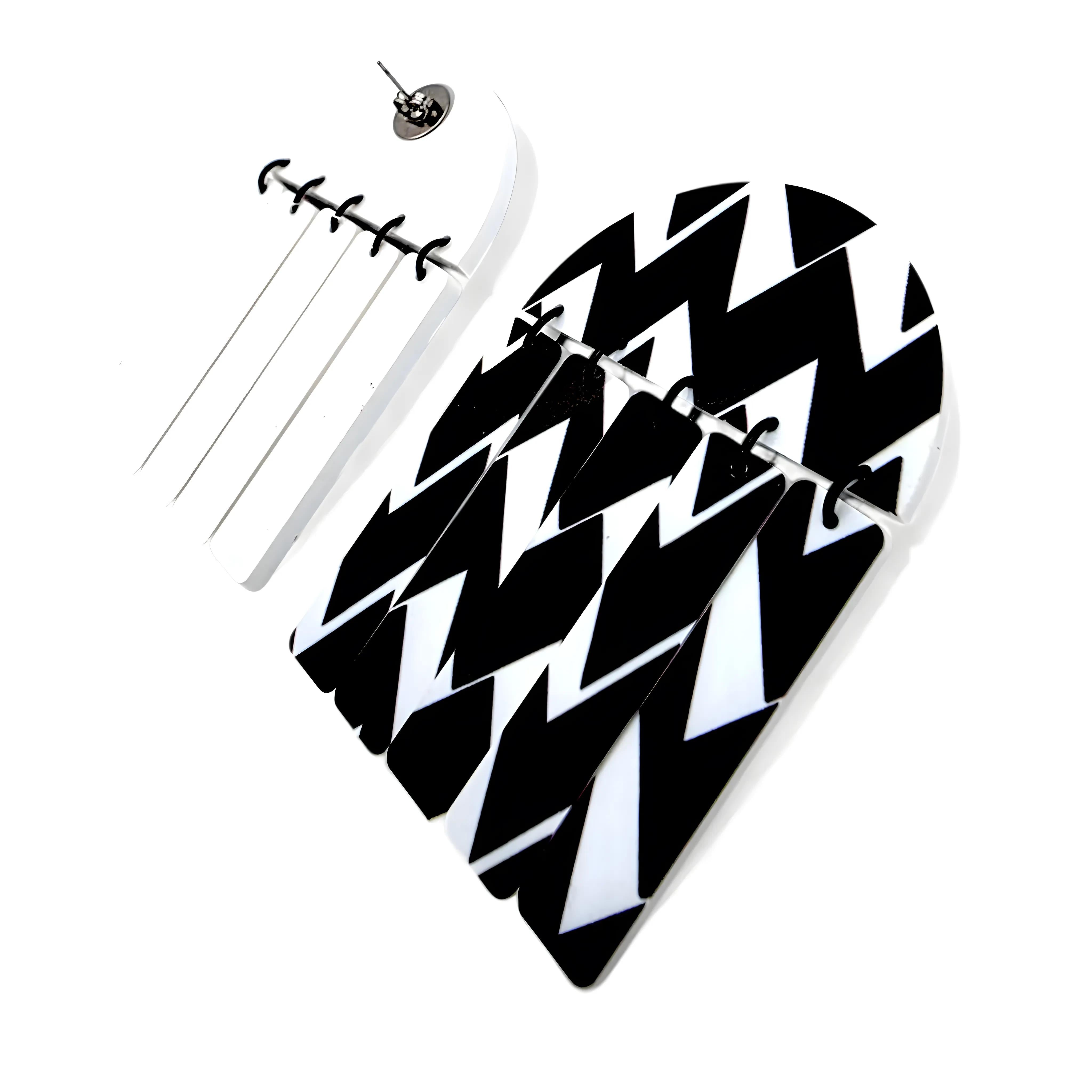 Brincos geométricos em preto e branco com padrão zigue-zague vistos de costas, mostrando o fecho