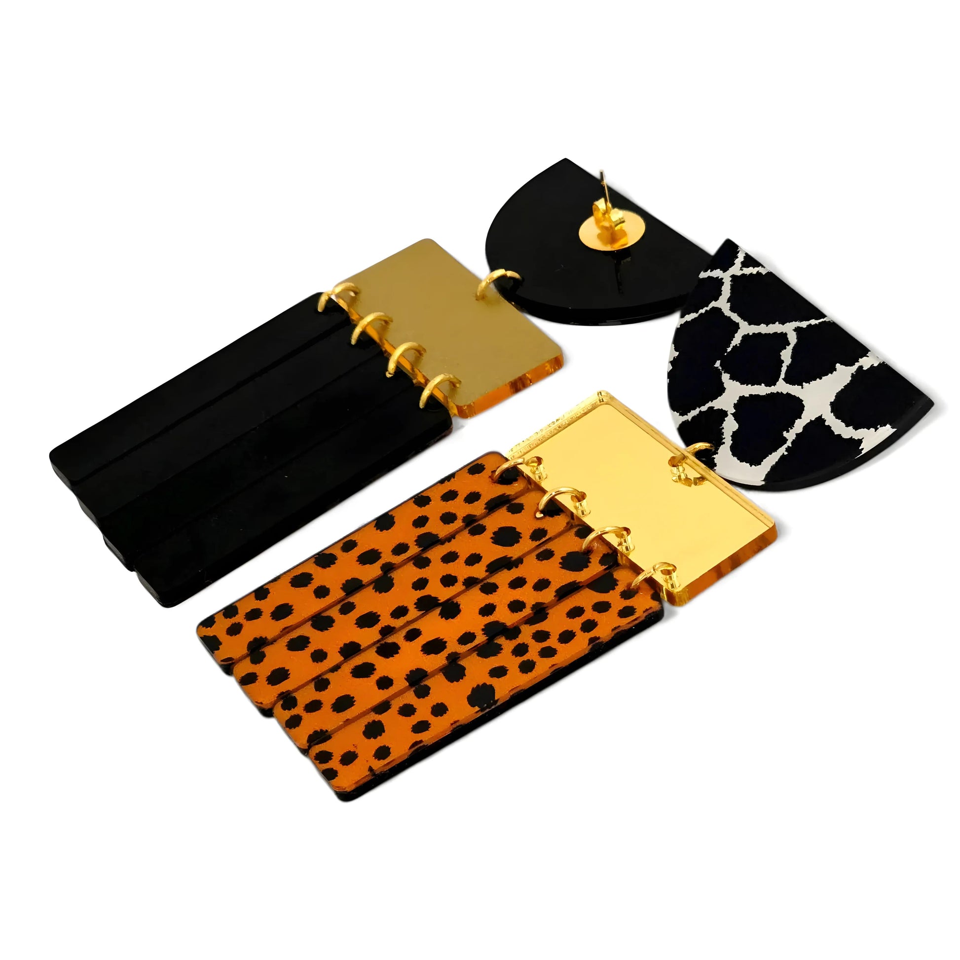 Brincos geométricos com mix de estampas animal print em preto, branco e laranja vistos de costas, mostrando o fecho dourado