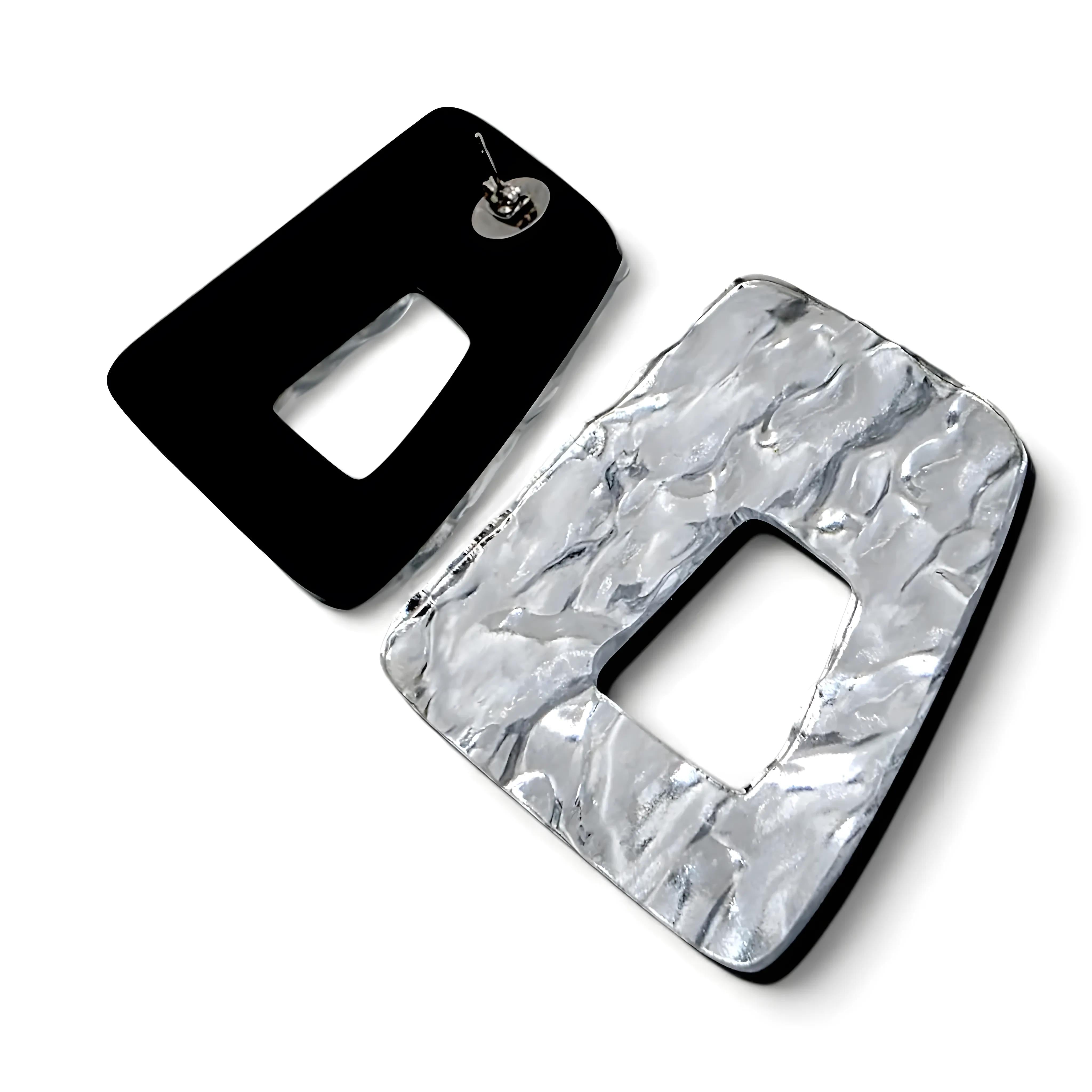 Brincos prateados com textura martelada e recorte geométrico vistos de costas, mostrando o fecho