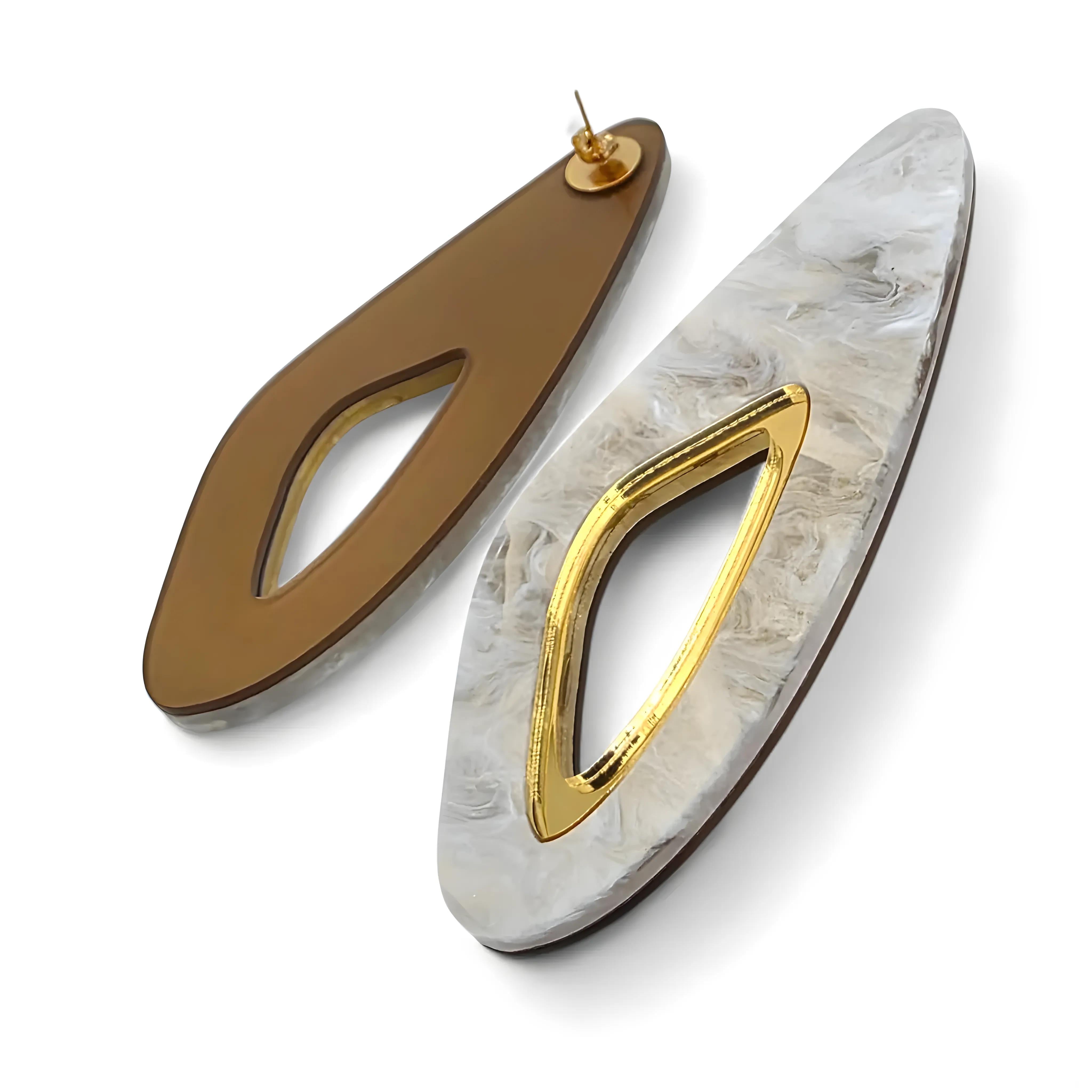 Brincos alongados com detalhe vazado dourado e verso liso em tom marrom, mostrando o fecho