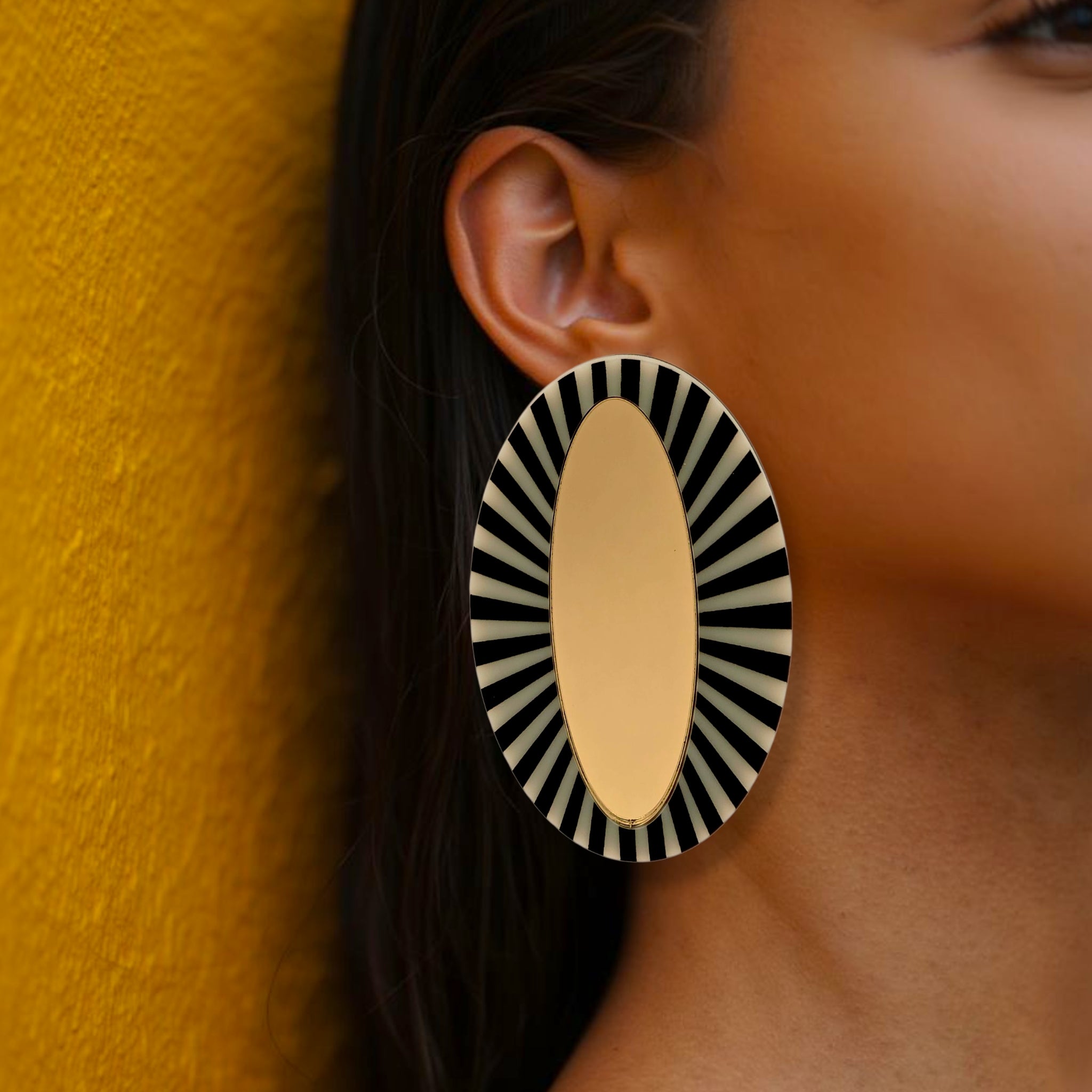 Brinco maxi oval dourado com detalhe listrado preto e branco em visual elegante