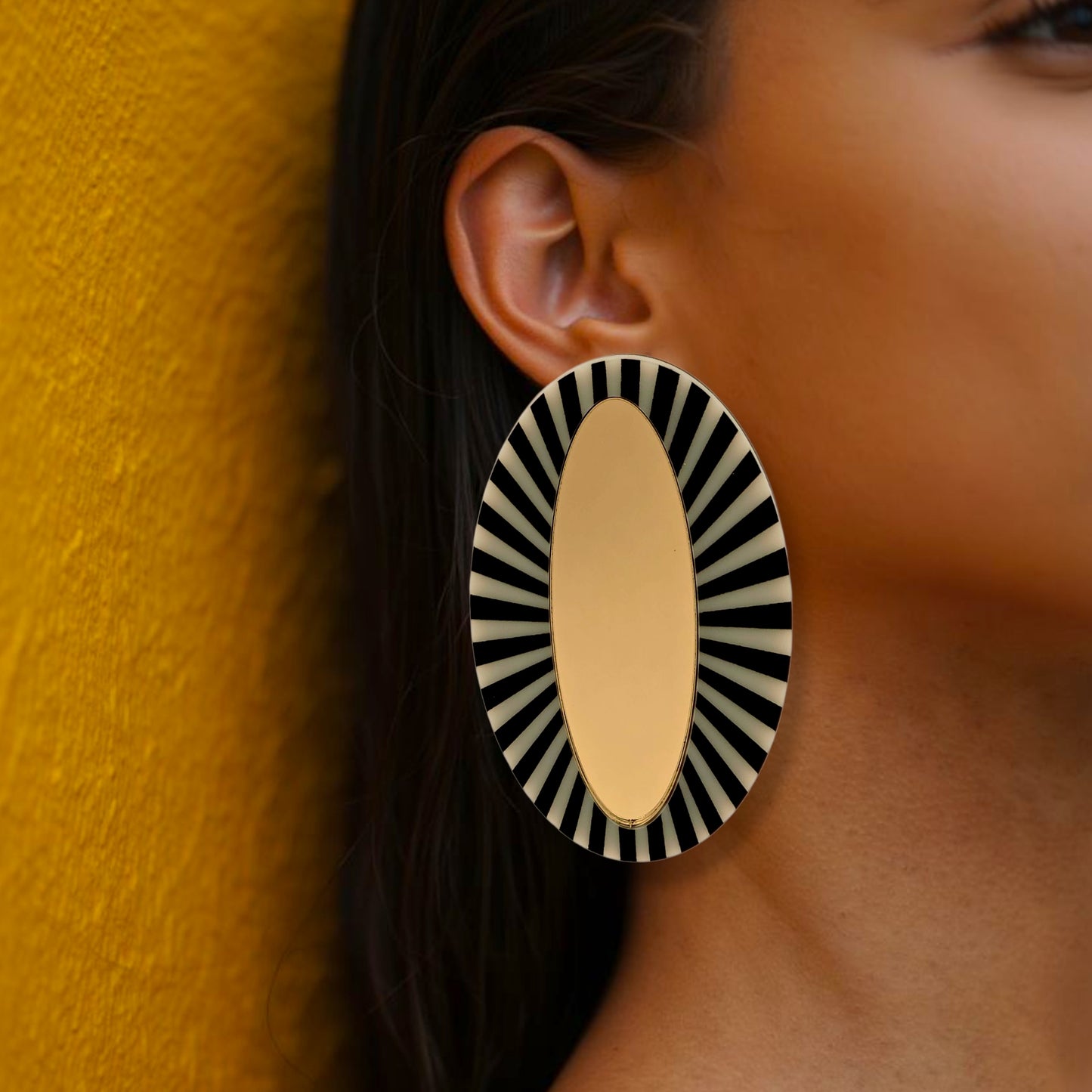 Brinco maxi oval dourado com detalhe listrado preto e branco em visual elegante