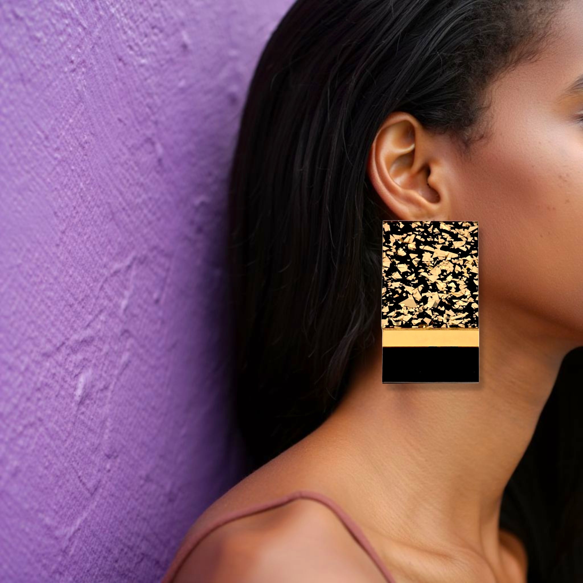 Brinco grande retangular preto e dourado marmorizado usado na orelha de uma mulher