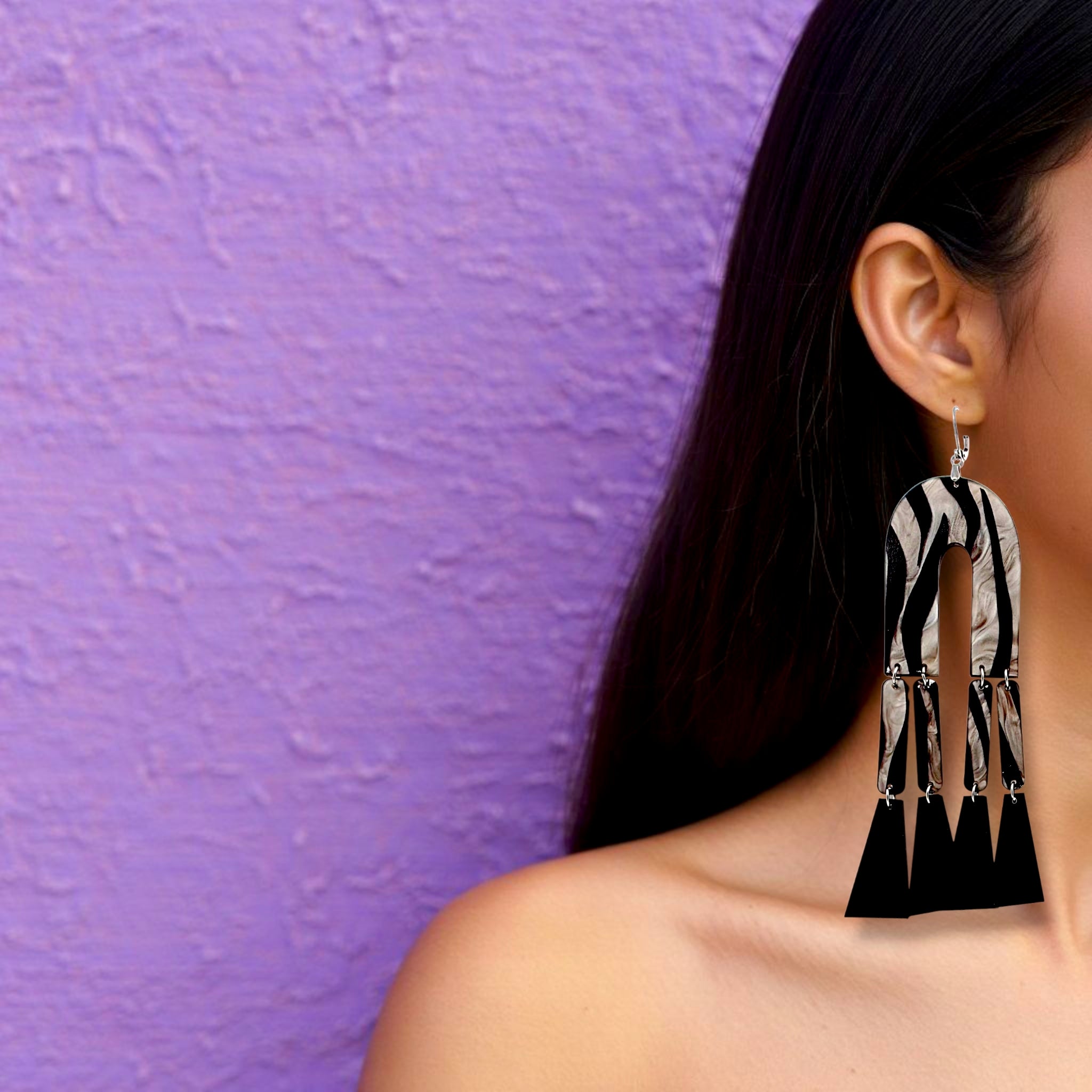 Brinco grande geométrico longo com estampa zebra em preto e branco usado na orelha de uma mulher