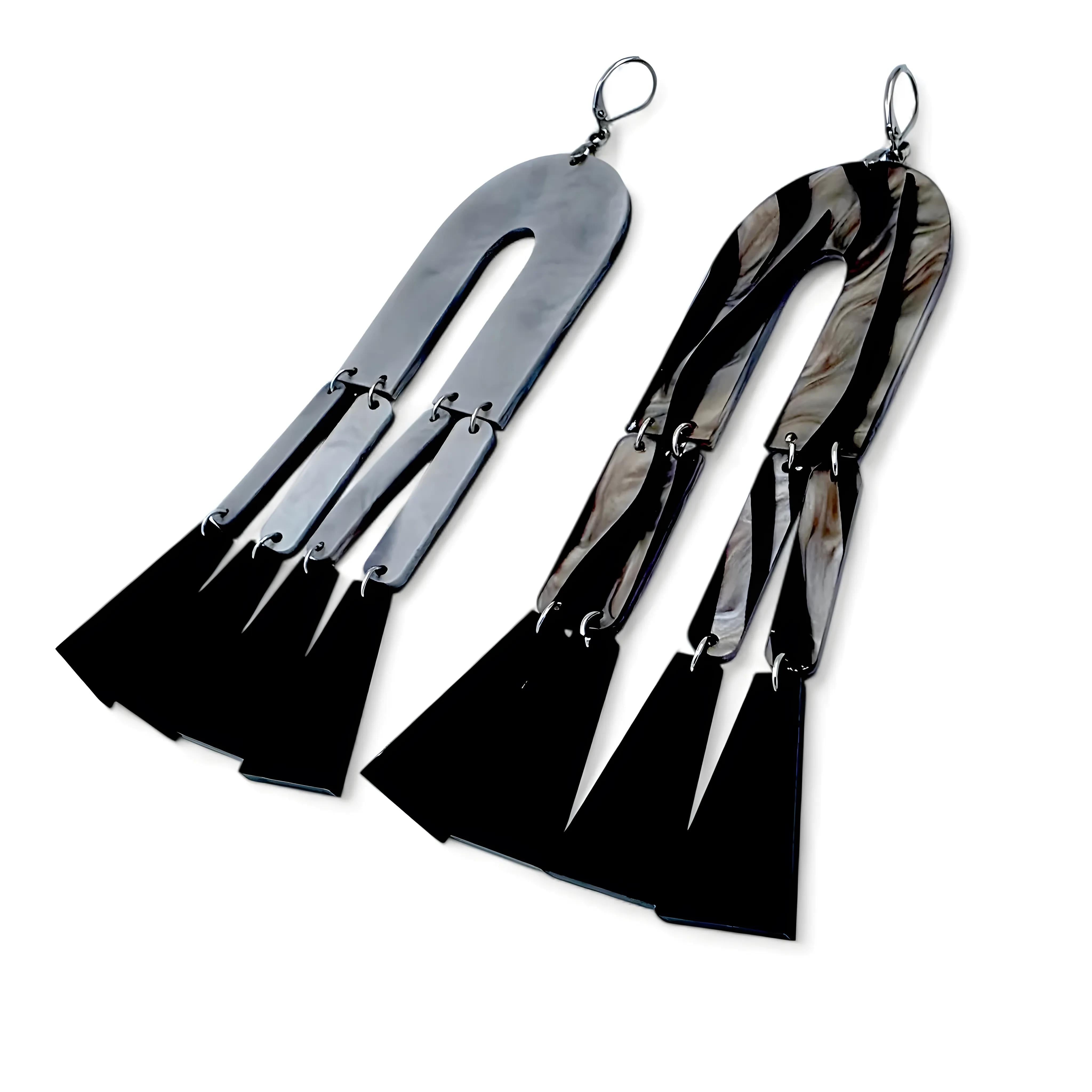 Brincos geométricos com estampa zebra em preto e branco vistos de costas, mostrando o fecho prateado