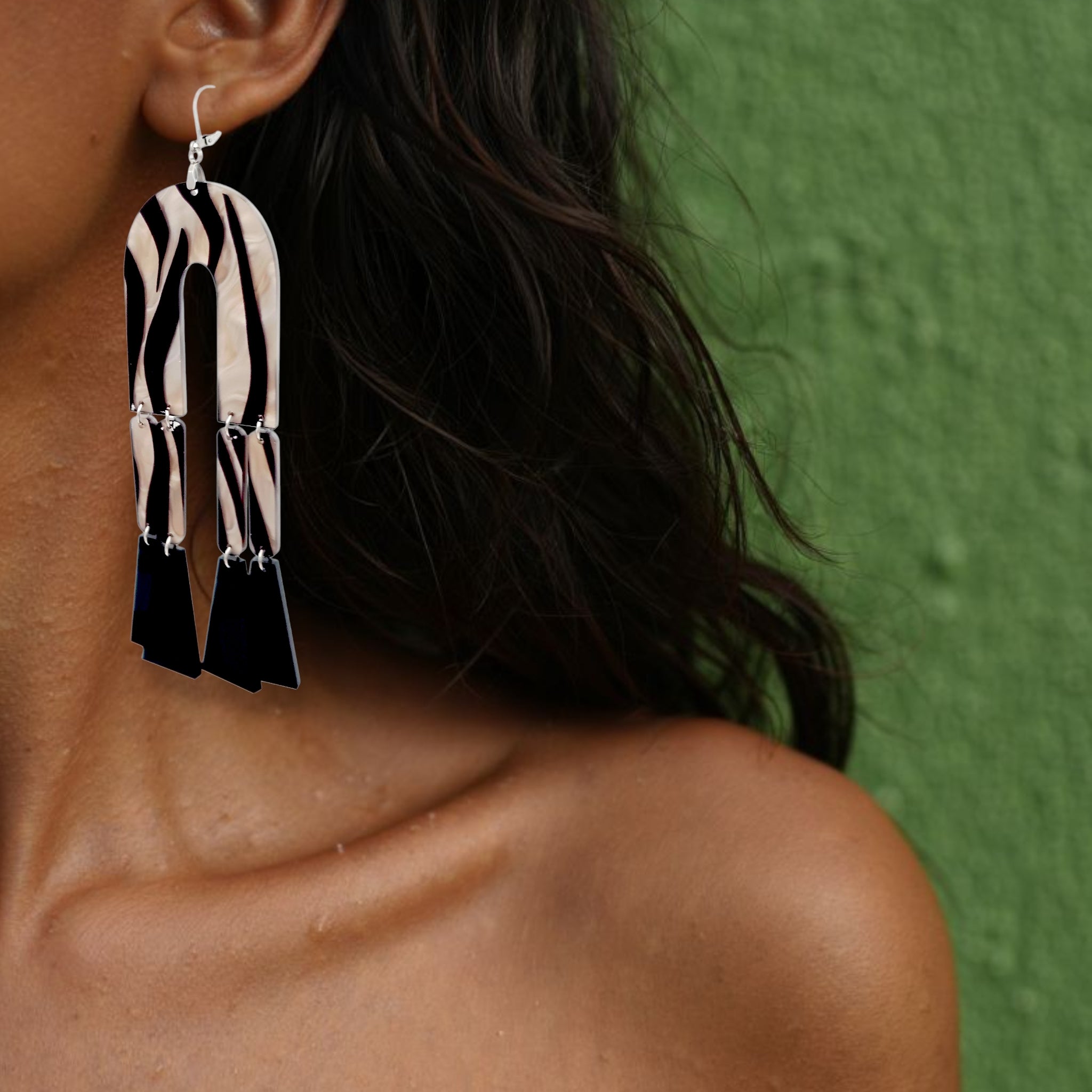 Brinco médio geométrico longo com estampa zebra em preto e branco usado na orelha de uma mulher